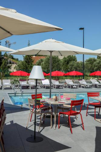 a table and chairs with umbrellas next to a pool at ibis Orange Centre in Orange