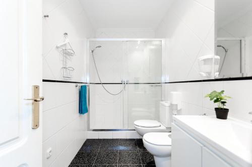 y baño blanco con ducha y aseo. en Pensión Goiko, en San Sebastián