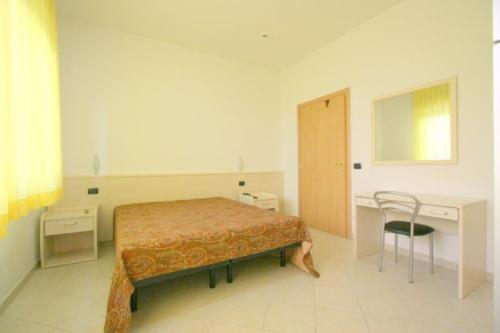 a bedroom with a bed and a desk and a chair at Hotel Sacramora in Rimini