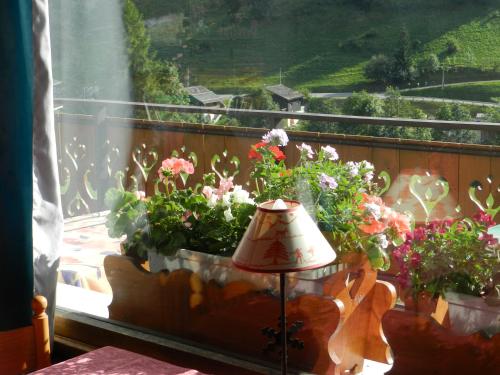 a window with flowers on a balcony with a lamp at Chalet-Hôtel du Borderan in La Clusaz