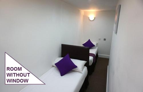 two beds with purple pillows in a room without window at Accommodation London Bridge in London