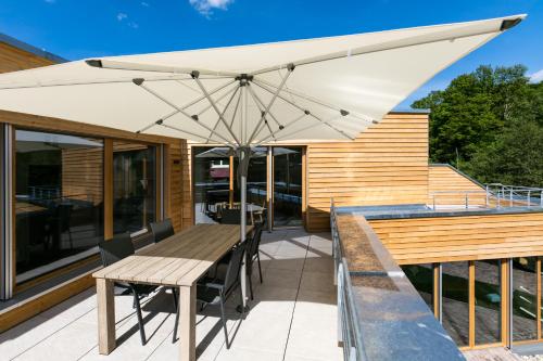 a wooden table with a white umbrella on a patio at Schwarzwaldstrand Ferienwohnungen in Bad Herrenalb