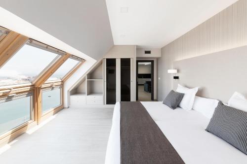a bedroom with a large bed and large windows at Apartahotel A Cetárea in Burela de Cabo