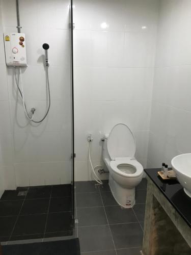 a bathroom with a shower and a toilet and a sink at De Nan Hotel in Nan