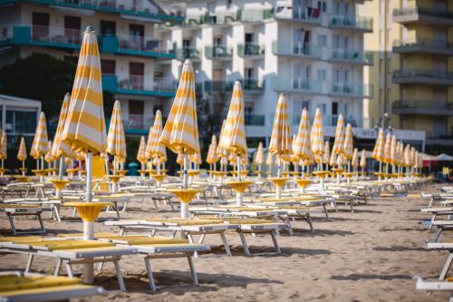 a bunch of chairs with umbrellas on a beach at Hotel Speranza in Lido di Jesolo