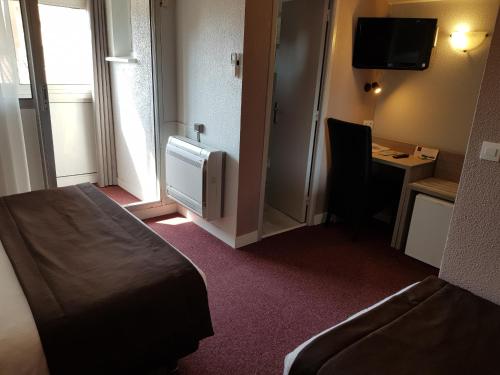 a hotel room with a bed and a desk and a television at Hôtel Port Beach in Gruissan