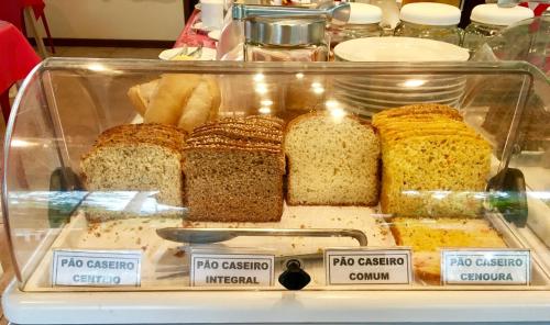 uma vitrine cheia de diferentes tipos de pão em Complexo de Pousadas Caraguatá na Ilha do Mel