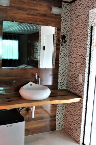 W łazience znajduje się umywalka i lustro. w obiekcie Suite JC w mieście Visconde De Maua