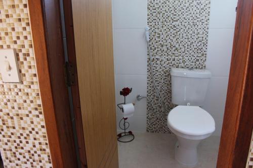 La salle de bains est pourvue de toilettes et d'une fleur. dans l'établissement Suite JC, à Visconde de Mauá