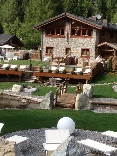 a large stone building with a deck and a house at La Tana dell'orso Hotel & SPA in Ponte di Legno