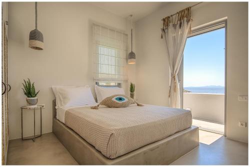 a bedroom with a bed with a view of the ocean at San Romano Villas in Agios Romanos