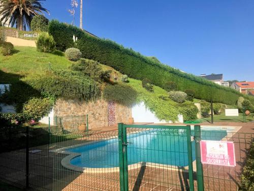 a fence around a swimming pool in a garden at Casa de Las Flores - Apartamento con jardín privado frente a la Playa de Comillas in Comillas