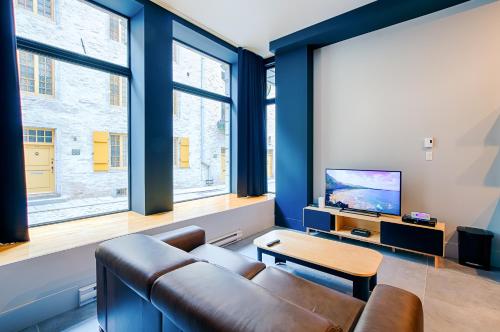 a living room with a couch and a tv at Les Lofts Notre-Dame - Par Les Lofts Vieux-Québec in Quebec City