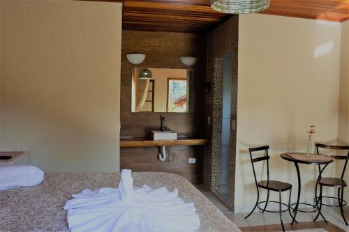 1 dormitorio con 1 cama, mesa y sillas en Chale Disco de Arado, en Visconde De Maua