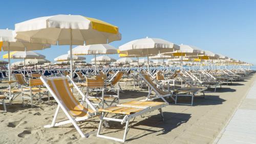 a row of chairs and umbrellas on a beach at Hotel Club i Pini - Residenza d'Epoca in Versilia in Lido di Camaiore