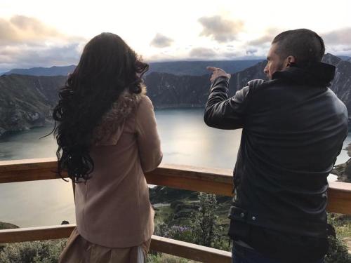 a man and a woman taking a picture of a lake at Samay Kirutoa Lodge in Quilotoa