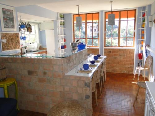 una cocina con una pared de ladrillo con mesas. en Casa Temporada Itaipava, en Petrópolis