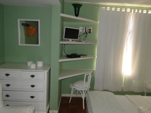 a bedroom with a bed and a desk with a computer at Casa Temporada Itaipava in Petrópolis