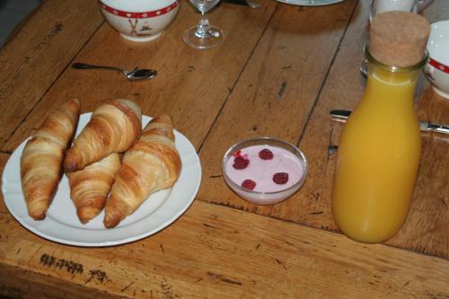 a table with a plate of croissants and a bottle of orange juice at Chambre d'hôtes "LES CRETS" in Mercury