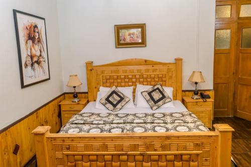 a bedroom with a wooden bed with two night stands at Pine Top Hotel Murree in Murree
