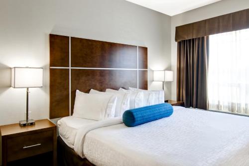 a hotel room with a large bed with a blue pillow on it at Canalta Martensville in Martensville