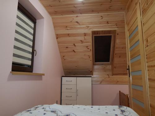 a small bedroom with wooden walls and a window at Domek Kruklanki in Kruklanki