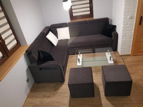 a black couch and stool in a living room at Domek Kruklanki in Kruklanki