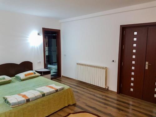 a bedroom with a green bed and a wooden floor at Casa DeLux in Băile Olăneşti