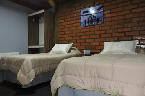 2 camas en una habitación con una pared de ladrillo en Maromava Patagonia en Puerto Natales