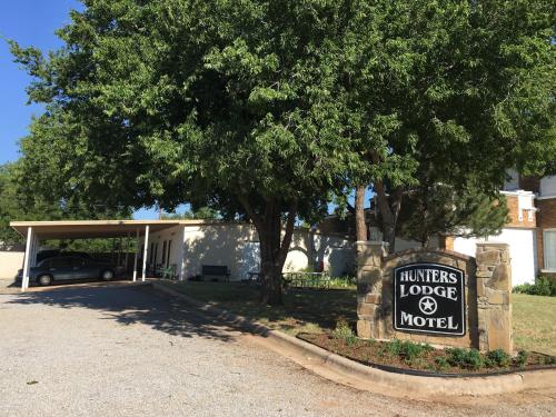 een bord voor een huis met een boom bij Hunters Lodge Motel in Paducah