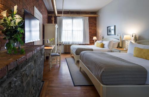 a hotel room with two beds and a tv at Auberge Saint-Pierre in Quebec City