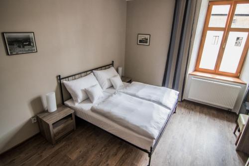 a bedroom with a bed with white sheets and a window at Pension Viktorin in Poděbrady