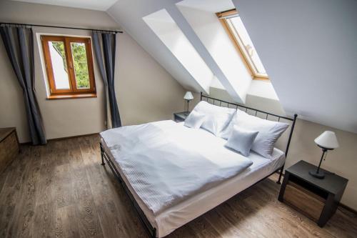 a bedroom with a bed with white sheets and windows at Pension Viktorin in Poděbrady