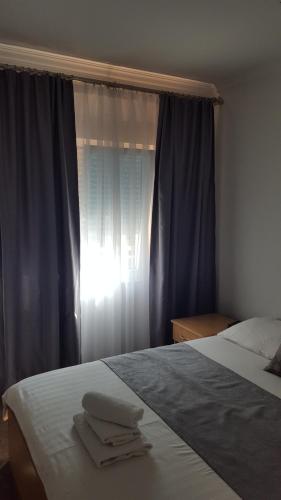 a bedroom with a bed and a window with blue curtains at Hotel Amicus in Mostar