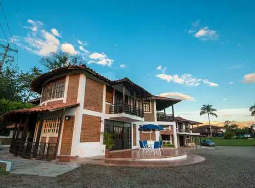 a brick house with a balcony and a yard at Finca Hotel Casa Nostra, Villa Manuela in Quimbaya