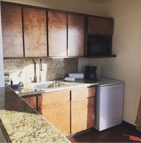a kitchen with wooden cabinets and a sink and a dishwasher at Dolphin Cove Motel in Pismo Beach