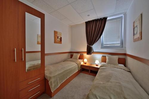 a bedroom with two beds and a mirror and a window at Apartman Afrodita 1 in Bardejovské Kúpele