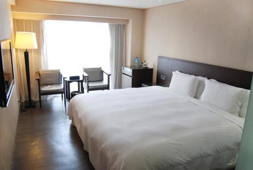 a hotel room with a large white bed and a table at Century Hotel Taoyuan in Taoyuan