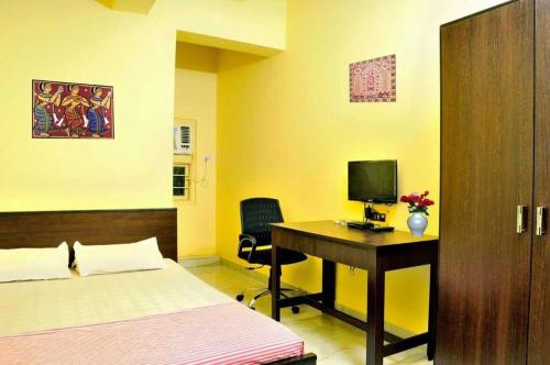 a bedroom with a bed and a desk with a computer at Bothra Guest House in Kolkata