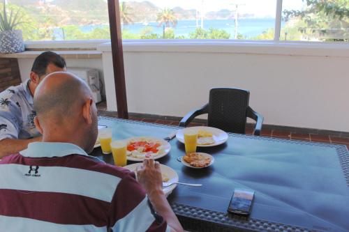 two men sitting at a table with food and orange juice at Hotel San Marcos Taganga in Taganga