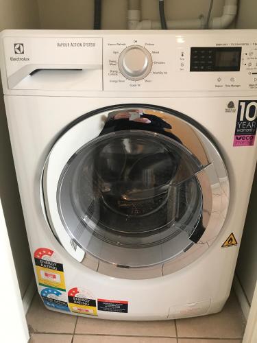 a white washing machine sitting in a room at Parkside Hotel & Apartments in Auckland