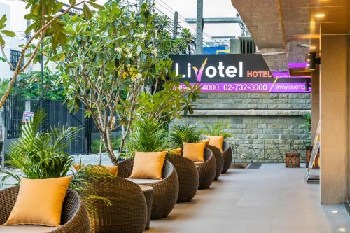 a row of wicker chairs with plants in a lobby at Livotel Hotel Hua Mak Bangkok in Bangkok
