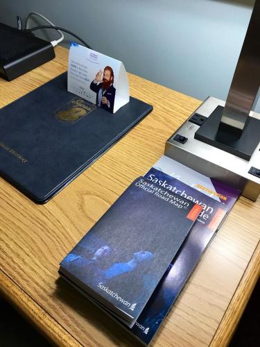 a desk with two brochures and a laptop at Super 8 by Wyndham Kindersley in Kindersley