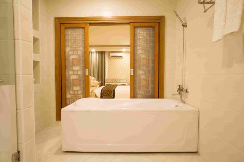 baño con bañera blanca y espejo en Anh Nguyet Hotel en Cà Mau