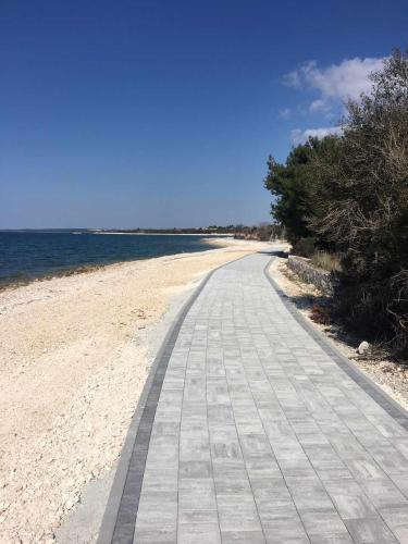 a road on a beach next to the water at Apartments Nogic in Peroj