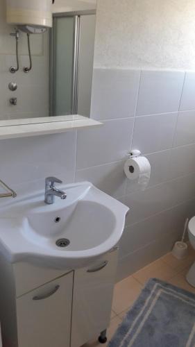 a bathroom with a white sink and a mirror at Nora Apartments in Povljana