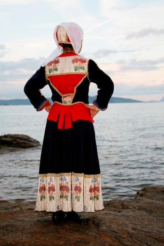 a woman is standing on the rocks near the water at Agriturismo Irghitula in Posada