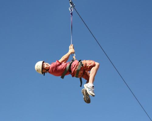 a man is hanging on a zip line at Zion Ponderosa Ranch Resort in Springdale