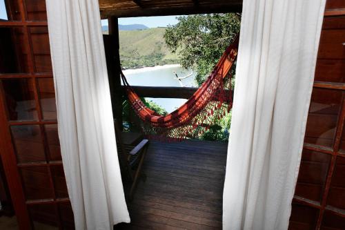 a balcony with a hammock and a view of a beach at Ilha de Toque Toque Eco Hotel in São Sebastião