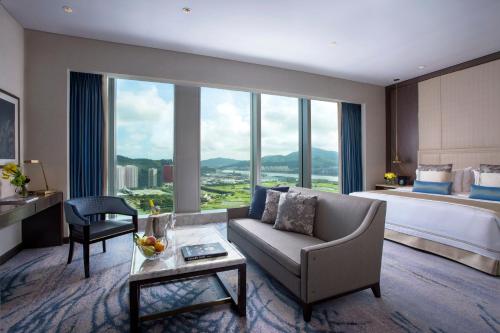 a hotel room with a bed and a couch and a table at Studio City Hotel in Macau